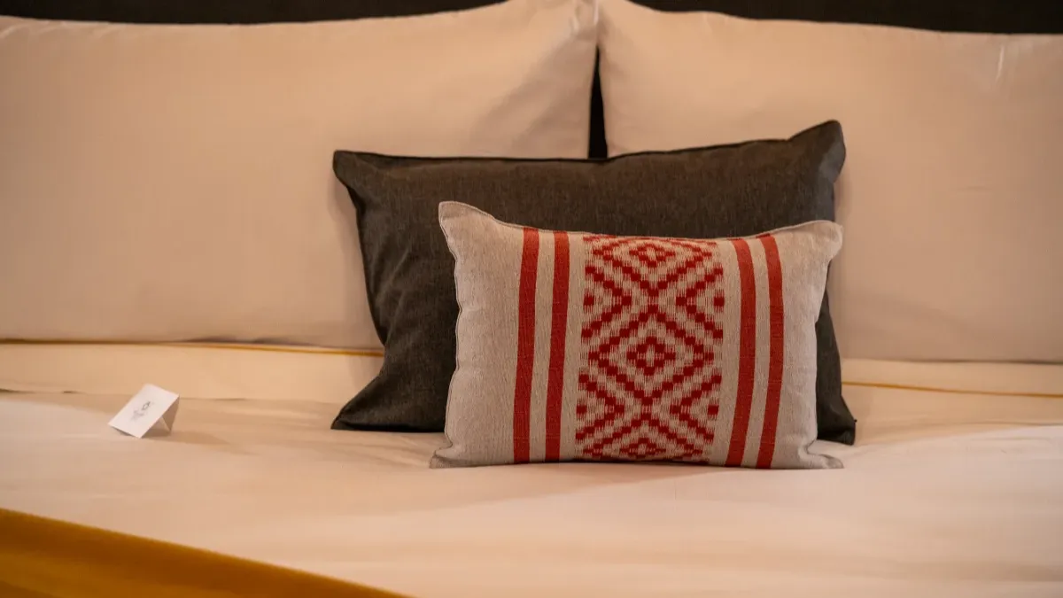 Cama con cojines y una carta en el Hotel Bellas Artes.