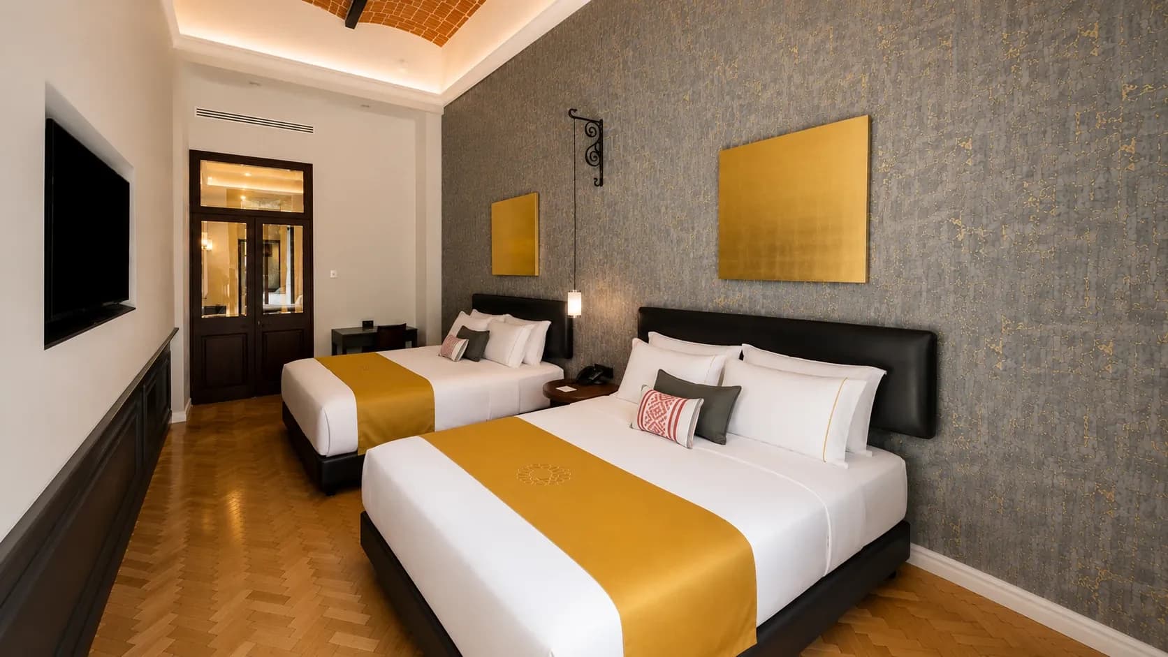 Quarto Suíte Queen com duas camas no Hotel Bellas Artes. Luxo total em espaço como em nenhum outro hotel. Vê-se o corredor e a televisão.