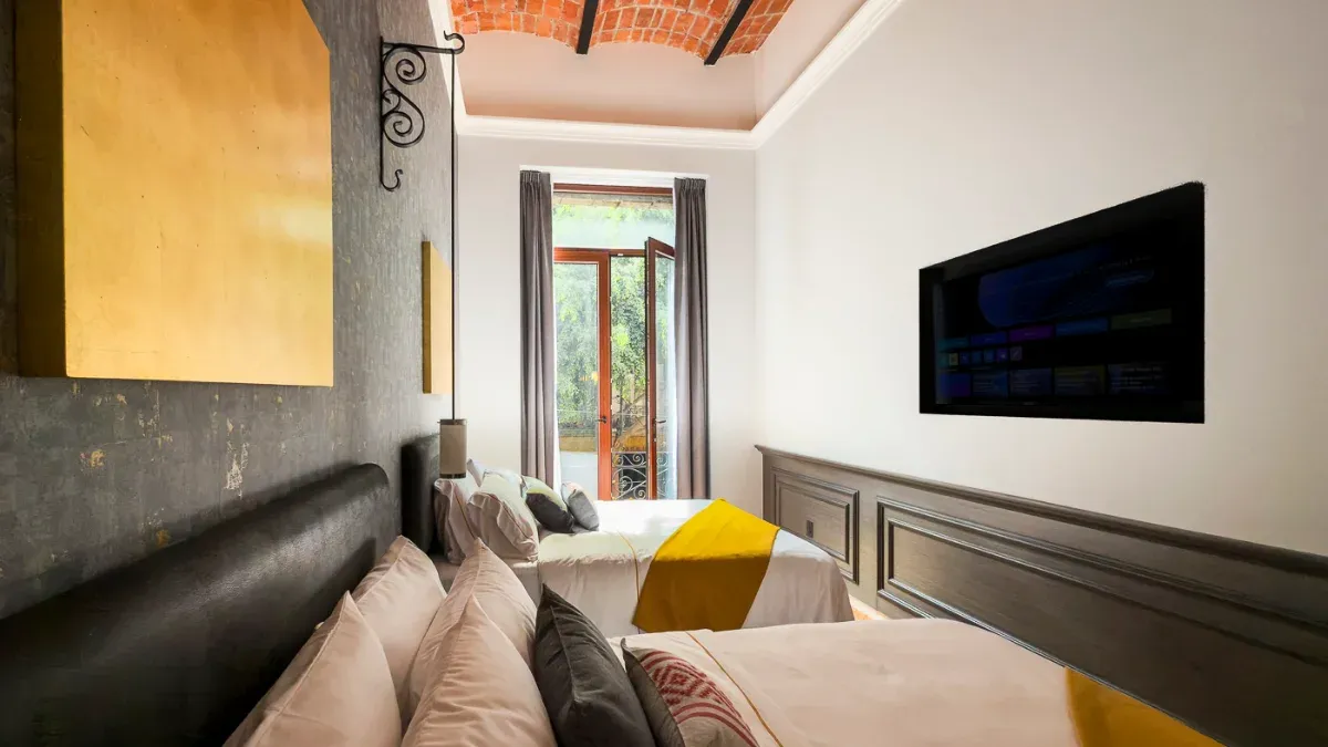 Suite queen avec deux lits à l'hôtel Bellas Artes. Un espace luxueux avec un grand couloir et une télévision.